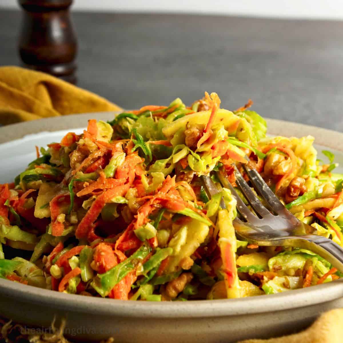 Brussels Sprout Slaw Recipe, a quick and simple side or appetizer recipe made with apple and carrot in a maple vinaigrette dressing.