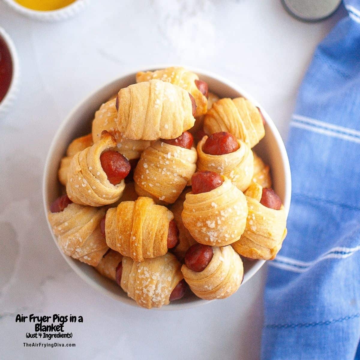 Air Fryer Pigs in a Blanket, a simple three ingredient appetizer or snack recipe featuring smoked sausages wrapped in crescent roll dough.